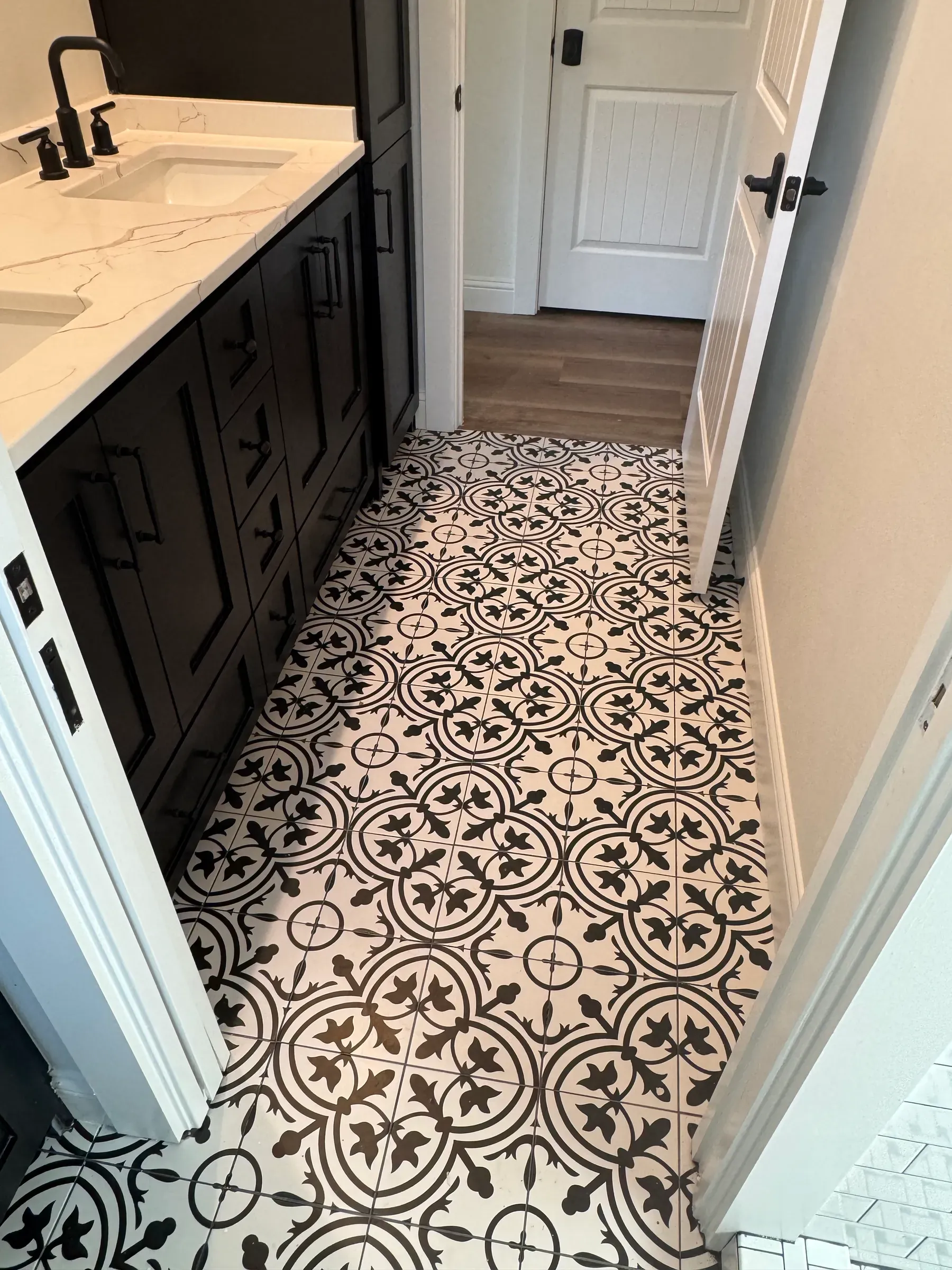 Bathroom with a black vanity and a black and white patterned cement tile floor