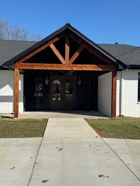 Finished home with a cedar timber-frame porch gable, white brick, and a new concrete walkway