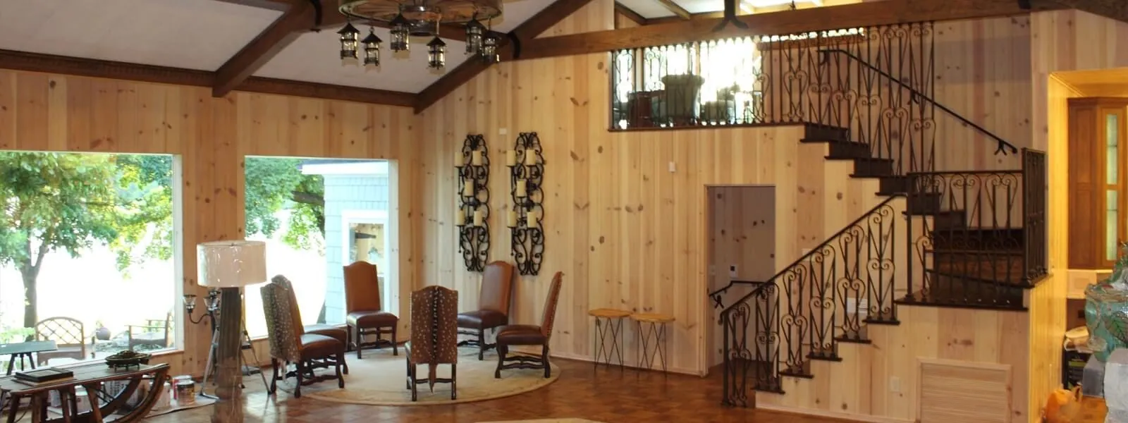 Great room rebuilt with new pine paneling, ceiling beams, and a wrought iron staircase