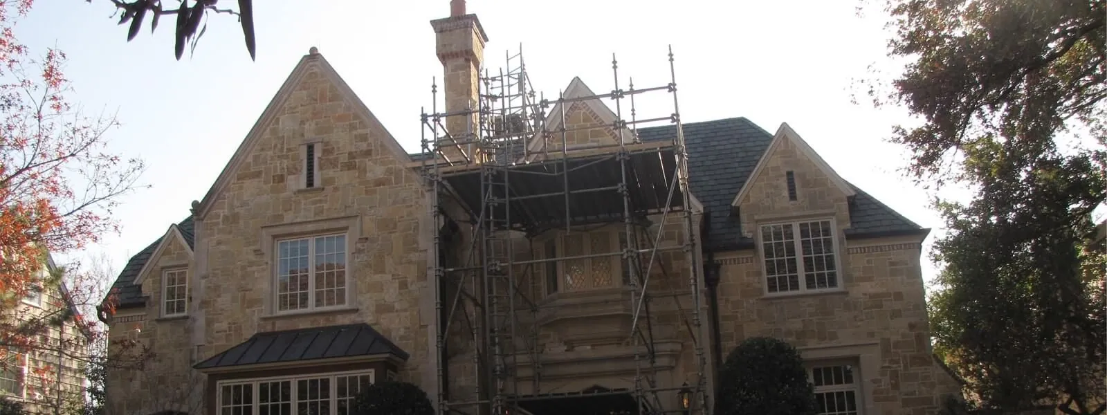 Two-story stone home with scaffolding during exterior repairs